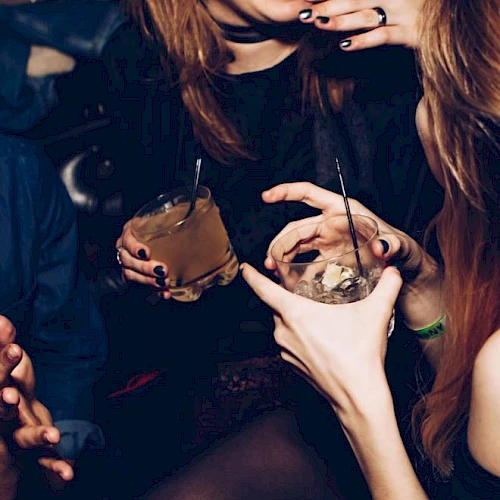 People are socializing at a party, holding drinks and chatting, creating a lively and festive atmosphere.