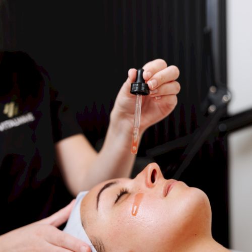 A person is receiving a beauty treatment or facial procedure, eyes closed, head resting on a pillow, hands gently working near the face.