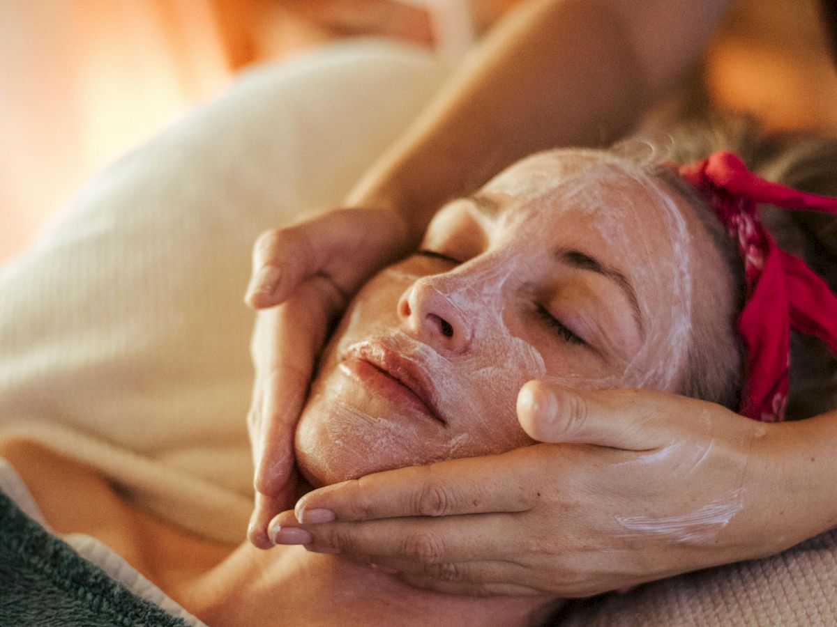 A relaxing facial massage scene, calm client with closed eyes, serene vibe, hands gently shaping the jawline and cheeks, soothing spa atmosphere.